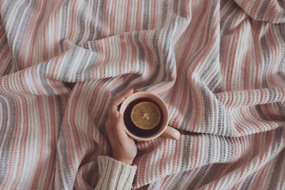 Una taza de café apoyada sobre una manta de rayas arrugada