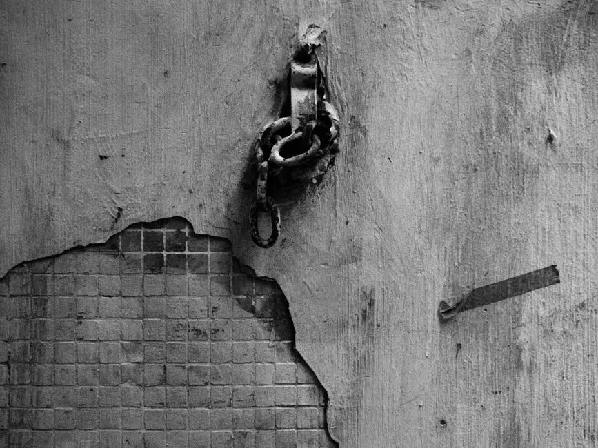 Cadena con candado colgando de una pared de hormigón agrietada